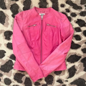 Rosa skinnjacka från Vero Moda - Säljer en snygg rosa skinnjacka från Vero Moda med dragkedja framtill och två bröstfickor med dragkedjor. Jackan har lång ärm och en figurnära passform. Perfekt för att addera färg till din outfit! Den verkar vara lite solblekt på vissa ställen, men jag tycker bara att det ger jackan karaktär 💓Storlek L, men sitter mer som en större S