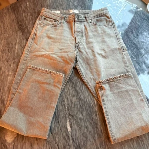 Grå jeansbyxor från Levis - Säljer ett par grå jeansbyxor från Levis med raka ben och klassiska fem fickor. Byxorna har normal passform och är tillverkade i denim. Perfekta för en avslappnad stil.