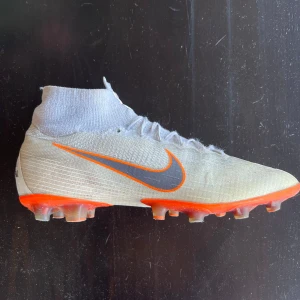 Nike Mercurial Superfly 6 - Nike mercurial Superfly 6 / Vapor 12 modellen. Skorna är i AG dobbar dvs spel på konstgräs. Storlek 41 o mycket bra skick inget släpp osv mycket dobbar kvar också. Dock ett litet hål på vänster strumpa se bild, samt att skosnörena är liiiiite slitna, dock inga problem. Skorna är från VM 2018