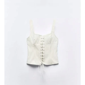 Vit randig korsettopp med snörning - Säljer populär vit korsettopp från zara.  Toppen har snygg snörning framtill!  Perfekt sommar- och festtopp! Jag säljer den då den inte passade mig. Helt ny och oanvänd med lappen kvar. 