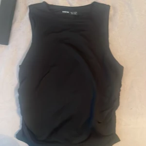 Svart ärmlös topp från SHEIN - Säljer en svart ärmlös topp från SHEIN med rund halsringning. Enkel och stilren design som passar till många olika outfits. Perfekt för varma dagar eller som lager under en jacka.