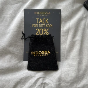 Silverfärgat halsband från Indossa by Sweden - Säljer ett stilrent silverfärgat halsband från Indossa by Sweden. Kedjan har ett detaljerat och flätat mönster som ger ett exklusivt intryck. Perfekt accessoar för att lyfta din outfit. Levereras i original svart tygpåse med guldfärgad logga. Man får med en kod med 20% rabatt på indossa också 