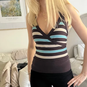 Randig  halterneck topp - Säljer en snygg halterneck topp med randigt mönster i brun, beige och turkos. Toppen har  v-ringning. Perfekt för sommaren! Xs-s