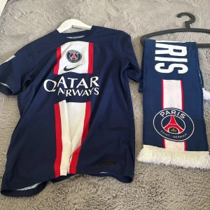 PSG Mbappé matchtröja och halsduk - Säljer en blå Paris Saint-Germain fotbollströja med Mbappé 7 på ryggen. Köpt i paris på deras affär för ca 1399 kr. Den är riktigt och endast använd några få gånger. Halsduken är också köpt i paris, priset diskuteras. Kan köpa separat.