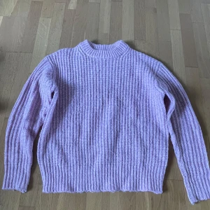 Rosa stickad tröja från 157 - Supermysig rosa stickad tröja från 157 i storlek XS. Tröjan har en grovstickad struktur, rund halsringning och långa ärmar. Perfekt för att hålla sig varm och snygg under kyligare dagar.
