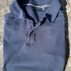 Pikétröja från J.Lindeberg - Mörkblå pikétröja från J.Lindeberg. Bra skick inga defekter eller liknande. Priset är alltid diskuterbart!