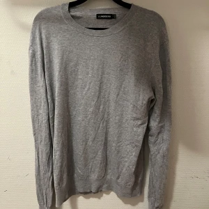 Grå tröja från J.Lindeberg - Säljer en stilren grå tröja från J.Lindeberg i mjukt material. Tröjan har rund halsringning och långa ärmar, perfekt för lager-på-lager eller som den är. Diskret logga på bröstet och klassisk passform.
