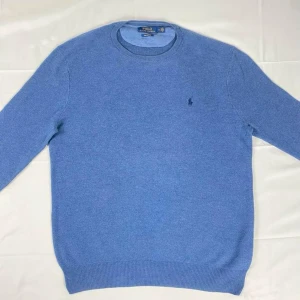 Blå tröja från Polo Ralph Lauren - Säljer en klassisk blå tröja från Polo Ralph Lauren i mjuk pima-bomull. Tröjan har rund halsringning, långa ärmar och diskret broderad logga på bröstet. Perfekt för en stilren och avslappnad look.