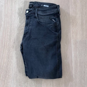 Replay Anbass - Säljer ett par svarta Replay jeans med klassisk femficksdesign. Byxorna har snygga detaljer som Replay-logga på bakfickan och svart patch i midjan. Perfekta för dig som gillar stilrena och tidlösa jeans.