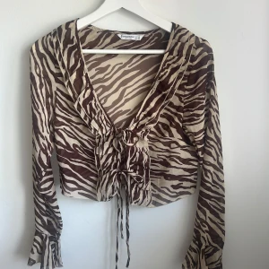 Zebramönstrad blus - Säljer en superfin blus i zebramönster med volanger och snören man knyter där fram, passar perfekt till sommaren! Har klippt av prislappen men den är aldrig använd💕