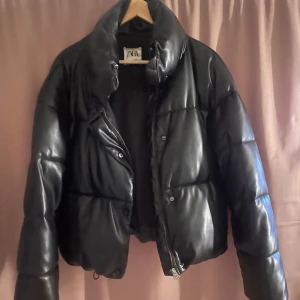 Svart pufferjacka från Zara - Säljer en svart pufferjacka från Zara i storlek S. Jackan har en hög krage, dragkedja framtill. Perfekt för många olika stilar. Endast använd fåtal gånger.