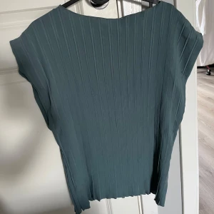 Grön ribbad topp - Säljer en stilren grön topp med ribbad struktur och korta ärmar. Toppen har en lös passform och är perfekt för dig som gillar enkel men trendig stil. Passar bra till både jeans och kjol. Använd endast 1 gång i stl. S från Zara.☀️😇🥰