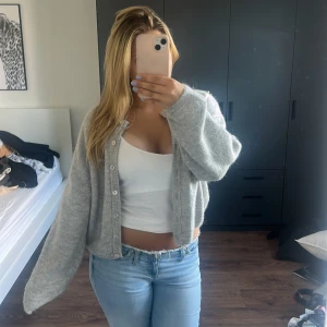 Grå stickad kofta från Gina Tricot - Mysig grå stickad kofta från Gina Tricot i oversized modell. Koftan har långa ärmar, pärlemorknappar framtill och är tillverkad i ett fluffigt material.💗💗Säljer då jag inte har fått den till användning. Hör av er vid frågor eller fler bilder!💗