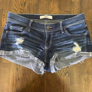 Mörkblå jeansshorts Hollister - Snygga mörkblå jeansshorts från Hollister med slitna detaljer och fransig kant. Bra skick. Storlek w27 men passar både större och mindre. Skriv om du har funderingar, priset kan disktuteras!💓