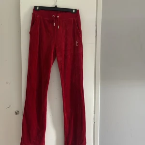 Röda velourbyxor Juicy Couture XS - Röda velourbyxor från Juicy Couture med snörning i midjan och fickor. Klassisk Juicy-logga i strass på baksidan. Som nya bara använt 2 gg💕