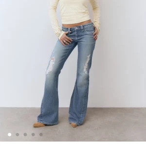Blå bootcut jeans med slitningar - Säljer ett par blå bootcut jeans från Gina, jeansen har låg midja och snygga slitningar på låren och knäna. Det finns ett litet hål vid slitningarna på ett utav knäna men det syns knappt, jeansen är bara använda ett par gånger så de är i bra skick. Pris går att diskutera. 