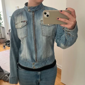 Ljusblå jeansjacka från Diesel - Säljer en snygg ljusblå jeansjacka från Diesel med coola detaljer som ståkrage med tryckknappar, dragkedja framtill och två bröstfickor med knappar. Jackan har en figurnära passform och passar strl S/M❤️💕