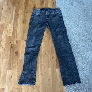 Gråa Levi’s 501 Jeans 32/34 - Klassiska gråa Levi's 501 jeans med rak passform och knappgylf. Jeansen har fem fickor och är tillverkade i slitstarkt denim. Perfekta för dig som gillar en tidlös och clean look. Storlek W32 L34. Skick 8/10.
