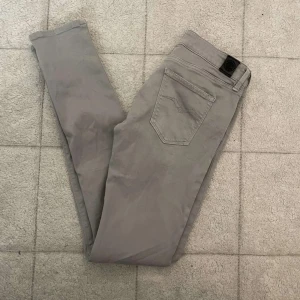 Grå Replay slim jeans - Snygga grå jeans från Replay med klassisk femficksdesign och smal passform. Byxorna har diskreta sömmar och en stilren look, perfekta till sneakers eller boots. Materialet är mjukt och stretchigt för extra komfort.