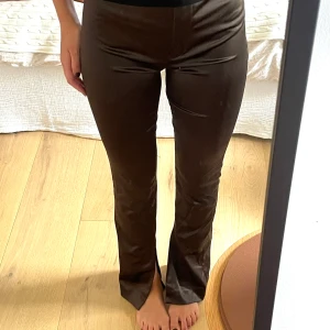 Bruna kostymbyxor från Massimo Dutti - Snygga bruna kostymbyxor från Massimo Dutti i glansigt material. Byxorna har hög midja, med lätt bootcut och snygga bakfickor. . använda 1 gång! 🤎