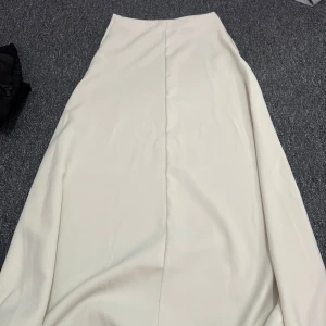 Ljusbeige långkjol från Cider - Supersnygg ljusbeige långkjol från Cider i slät satinliknande polyester. Kjolen har en enkel och stilren design med lätt utsvängd form och diskret söm framtill. Perfekt för dig som gillar minimalistisk och clean stil. Använd 1 gång. Priset kan diskuteras 😊💕