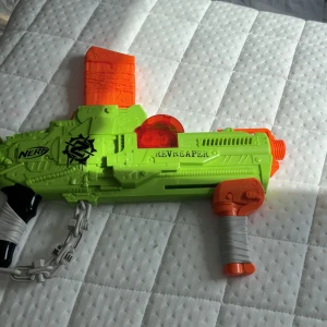 Nerf Gun  - Bilderna visar en leksakspistol från Nerf, modell Revreaper, i neonfärger med coola detaljer och tillhörande magasin. Detta är ingen bok, utan en leksak som passar för actionfyllda lekar och battles med vänner.