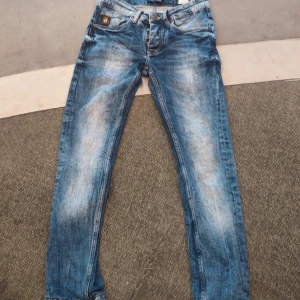 Blå Armani Jeans med AJ-detalj - Snygga blå jeans från Armani Jeans med AJ-läderpatch på fickan och klassisk femficksdesign. Jeansen har slitna detaljer och ljusa partier för en cool, använd look. Tillverkade i bomull och har raka ben med normal passform.