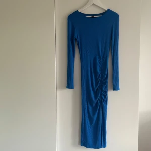 Blå ribbad långklänning med rynk - Snygg blå långklänning med ribbad struktur och långa ärmar. Klänning har en slits på sidan. Klänningen är köpt på New Yorker och är i bra skick. 💙💙💙