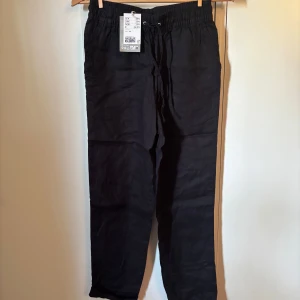 Svarta linnebyxor med snörning XS NYA - Svarta linnebyxor från H&M i storlek XS. Byxorna har elastisk midja med snörning och raka ben. Perfekta för en chill och avslappnad stil, tillverkade i svalt linne som passar bra när det är varmt ute. Oanvända med prislappen kvar. 