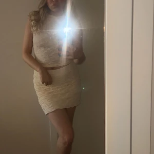 Beige kortkjol med matchande topp - Snygg beige kortkjol med matchande topp. Kjolen har en tight passform. Storlek Small och använt 2 gånger, inget fel på settet utan kommer bara inte till använding:) 