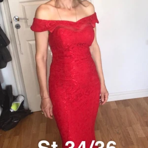 Röd axelbandslös klänning - Elegant röd klänning med offshoulder-design och vacker spetsdetalj. Klänningen har en lång, figurnära passform och en dramatisk slits baktill. Perfekt för speciella tillfällen.