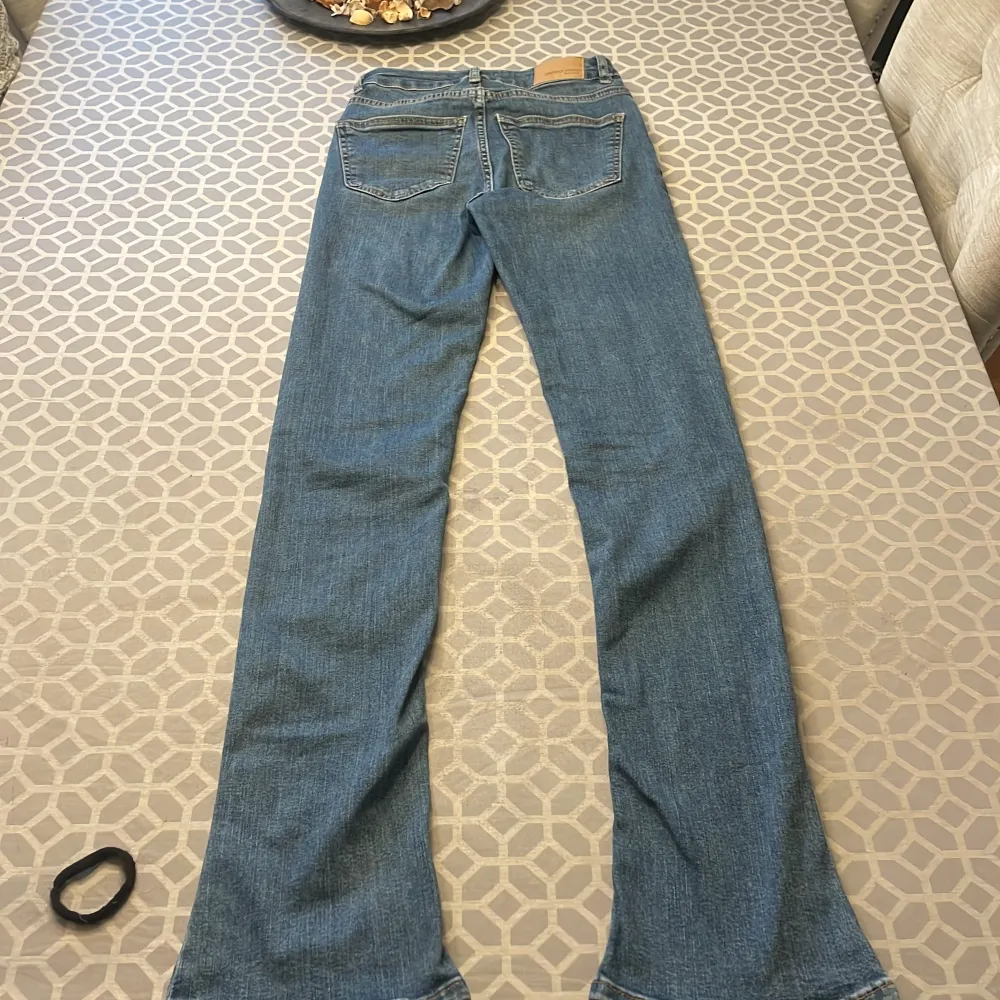 Säljer ett par snygga blå bootcut jeans med hög midja. De har en klassisk femficksdesign och är perfekta för en avslappnad stil. Jeansen är tillverkade i ett bekvämt denimtyg som ger en skön passform.. Farkut & Housut.