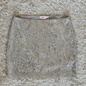 Glittrig kjol från Nelly - Snygg glittrig kjol från Nelly i en kort modell. 