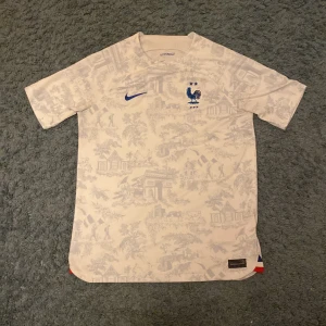 Vit fotbollströja från Nike - Säljer en vit fotbollströja från Nike med Frankrike. Den har fina detaljer över hela tröjan utan namn eller nummer på ryggen. Storleken på tröjan passar folk 158-170.