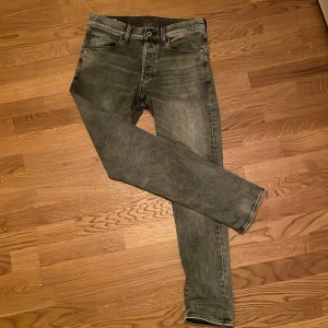 Grå jeans från G-Star RAW - Säljer ett par grå G-Star RAW 3301 jeans med regular tapered passform. De har en klassisk femficksdesign och en snygg tvättad look. Perfekta för en stilren vardagsoutfit. Passar 178-185