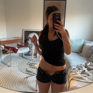 Svarta jeansshorts - KAN BYTA MOT LÅGMIDJADE JEANSSHORTS. Snygga svarta jeansshorts med låg midja och fransiga kanter. De har en klassisk design med fem fickor och knappgylf. De står storlek 36 men skulle säga mer 32/34