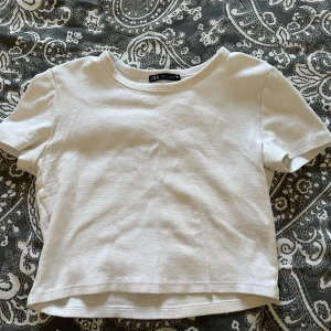 Vit kortärmad topp från Zara - Säljer en enkel och stilren vit kortärmad topp från Zara. Använd några gånger men fortfarande i perfekt skick 💗