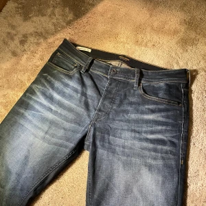 Mörkblå jeans från Jack & Jones - Snygga mörkblå jeans från Jack & Jones med klassisk femficksdesign och kontrastsömmar. Slim, storlek 32/32