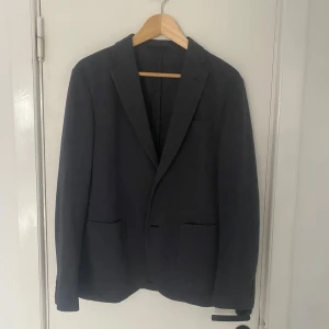 Grå kavaj från Uniqlo - Snygg grå kavaj från Uniqlo i en klassisk design. Tillverkad i polyester med en stilren passform. Perfekt för både formella och avslappnade tillfällen. Kavajen har två framfickor och en enkel knäppning framtill. Passar S perfekt. Skriv om ni har några övriga frågor🙌
