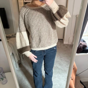 Randig stickad tröja från Design by Si - Säljer en mysig randig tröja från Design by Si. Tröjan är stickad i beige och bruna toner med långa ärmar och en avslappnad passform. Perfekt för kyliga dagar. Tillverkad i Italien med en blandning av akryl, mohair och polyamid.