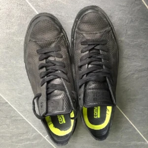 Svarta skinn sneakers från Converse 42 - Snygga svarta Converse Chuck Taylor sneakers med perforerat mönster och klassisk snörning. Skorna har en kontrasterande gul innersula som ger en cool touch. Perfekta för en avslappnad stil.väldigt lite använda