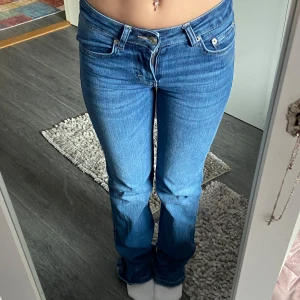 Blå lågmidjade bootcut jeans  - Snygga blå jeans med bootcut och låg midja. De har klassiska fem fickor och en knappgylf. Perfekta för en avslappnad stil.🦋