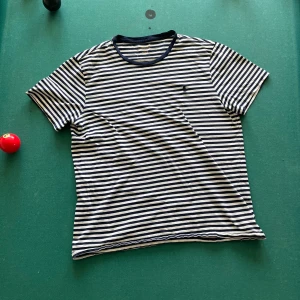 Randig t-shirt från Ralph Lauren - Sommrig T-shirt från Polo Ralph Lauren! Skönt randigt mönster som är perfekt för sommar kvällar vid havet! Storlek L men passar lite närmare åt M hållet. Skriv vid minsta fundering eller fråga!