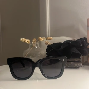 Svarta solglasögon chimi - Snygga svarta solglasögon med bred båge och mörka linser. Perfekta för en stilren look och skyddar mot solen. Passar till alla tillfällen och ger en cool touch till din outfit.