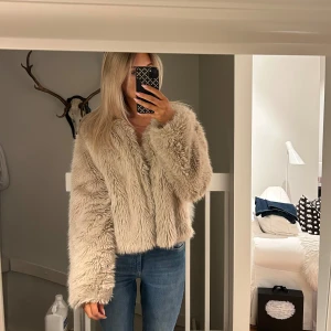 Beige pälsjacka - Säljer en fluffig och trendig beige pälsjacka. Jackan har fin passform och långa ärmar, perfekt för att hålla dig varm och stilren. Den är idealisk för höst och vinter och ger en lyxig känsla till din outfit.