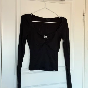 Svart långärmad topp från Gina Tricot - Säljer en svart långärmad topp från Gina Tricot med en söt liten rosett framtill. 