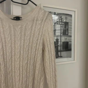 Beige stickad tröja från H&M - Säljer en mysig beige stickad tröja från H&M med ett klassiskt flätmönster. Snugg o stilren