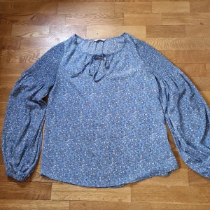 Sommarblus med ballongärm - Superhärlig blus med snyggt fall och knytning i halsen. Smock på ovandelen av armen. 