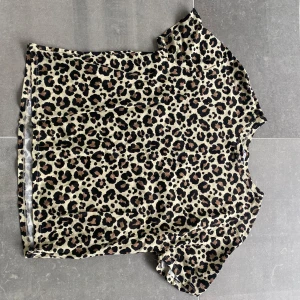 Leopardmönstrad topp - Säljer en snygg topp med leopardmönster och korta ärmar. Toppen har rund halsringning och är i mjukt material, perfekt för dig som vill sticka ut lite extra.