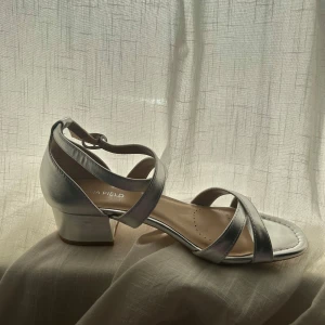 Silvriga klackskor - Säljer ett par helt oanvända silvriga klackskor i storlek 38🤍klacken är ca 4cm hög! Säljer en blå balklänning som passar till, skriv om ni har frågor eller funderingar!🤍